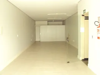 Vista de um corredor interno com paredes brancas e piso claro.