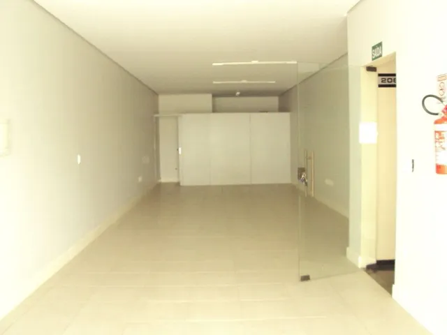 Vista de um corredor interno com paredes brancas e piso claro.