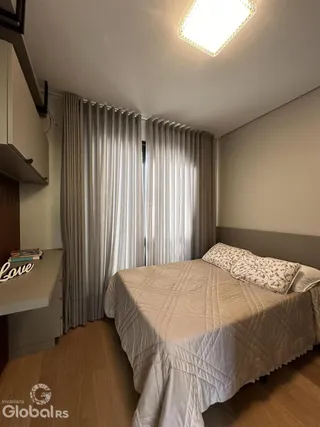 Quarto com cama e cortinas brancas.