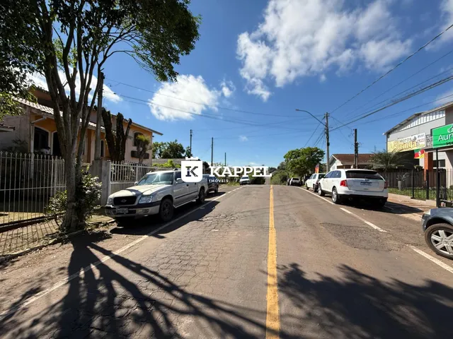 Vista externa de uma rua em Lajeado, Brasil, com veículos estacionados e vegetação ao lado.
