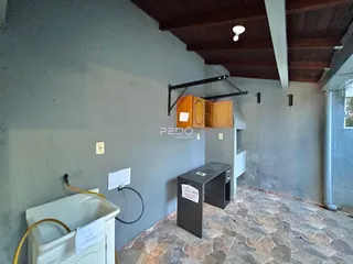 Interior de uma sala com teto de madeira exposto e paredes cinzas.