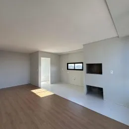 Ambiente interno de uma sala ampla com piso de madeira clara.