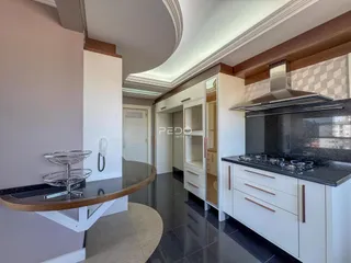 Vista da cozinha moderna com armários brancos e piso escuro.