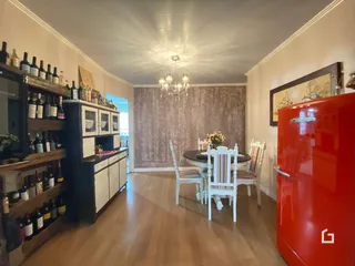 Ambiente interno de uma sala de jantar com piso de madeira e móveis de madeira escura.