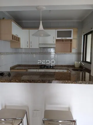 Vista da cozinha com armários brancos e bancada de granito.