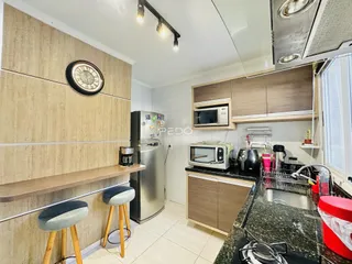 Imagem de uma cozinha moderna com armários de madeira e eletrodomésticos em Lajeado.