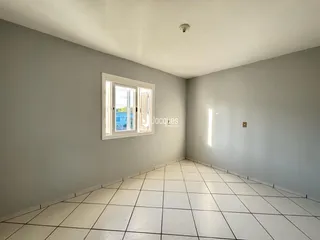 Ambiente interno de uma sala com piso de cerâmica branca e paredes cinzas.