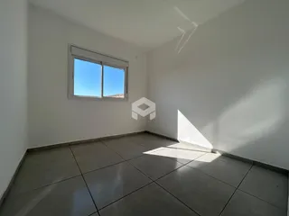 Ambiente interno de uma sala com paredes brancas e piso de cerâmica.