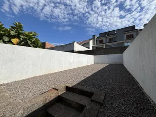 Vista externa de um terreno com muros e cascalho.