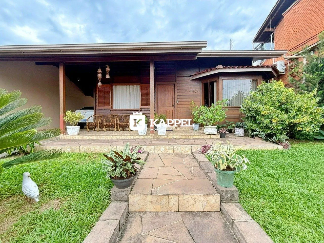 Fachada da casa com um pátio coberto e jardim.