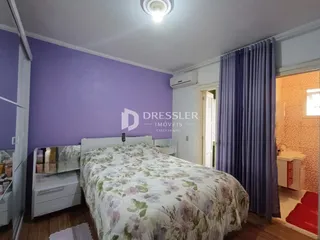 Quarto com paredes roxas e cama decorada em um imóvel no Brasil.