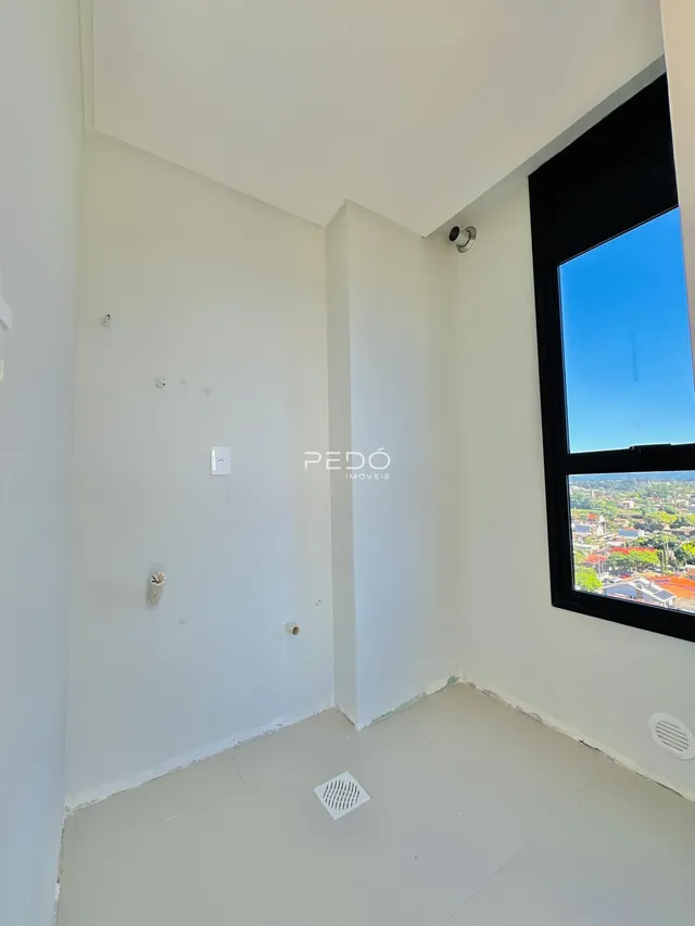 Vista de um canto de sala com paredes brancas e uma grande janela.
