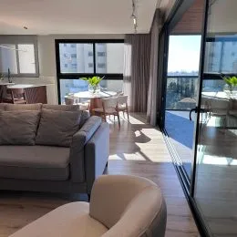 Foto interna de uma sala de estar com sofá e piso de madeira.