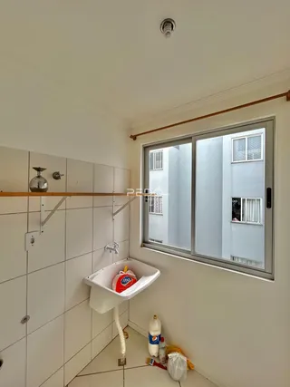 Interior de um banheiro com revestimento cerâmico branco e janela.