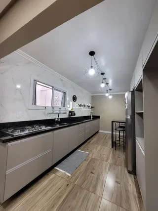 Vista da cozinha moderna com armários e piso de madeira clara.