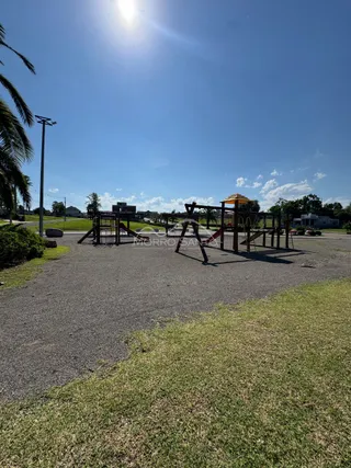 Foto de um playground externo com estruturas de madeira em uma área gramada.