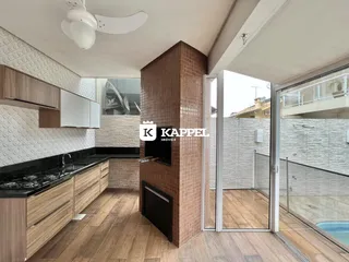 Cozinha moderna com armários de madeira e piso de madeira, com acesso a uma área externa com piscina.
