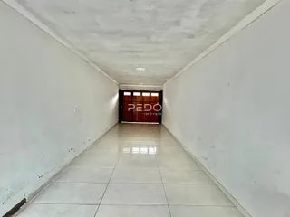 A foto mostra um corredor longo com paredes brancas e piso de cerâmica.