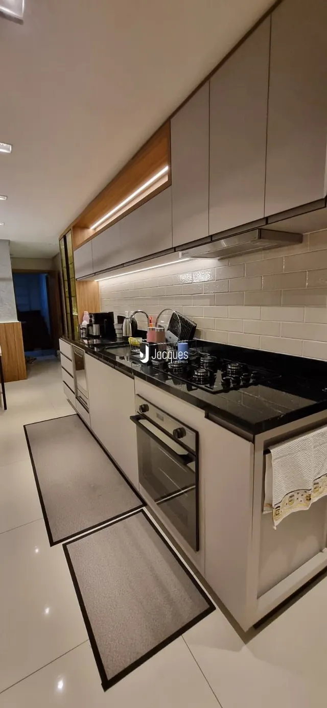Uma cozinha moderna com armários brancos e bancadas escuras.