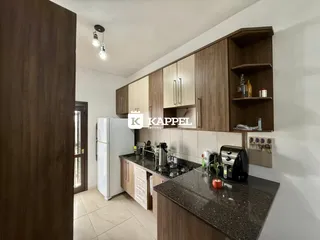 Cozinha moderna com armários de madeira e bancadas escuras.