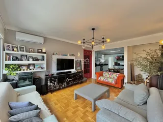 Sala de estar com piso de madeira e sofá cinza em um imóvel no Brasil.