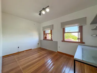 Sala de estar com piso de madeira e janelas.