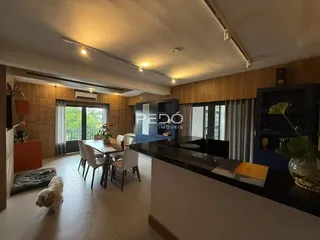 Ambiente interno de sala de jantar e cozinha com piso de cerâmica e painéis de madeira.