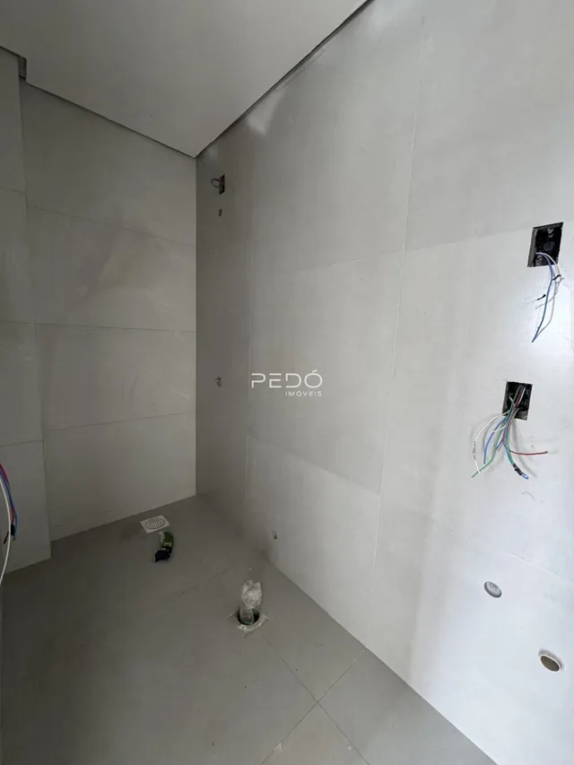 Interior de um cômodo com paredes e piso revestidos de cerâmica.