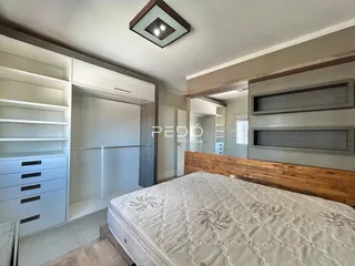 Quarto com armários embutidos e cabeceira de madeira.