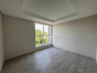A sala apresenta paredes claras e piso de madeira.