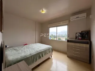 Quarto com cama e janela com vista para a paisagem urbana.