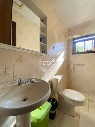 Foto de um banheiro interno com azulejos brancos e louças sanitárias.