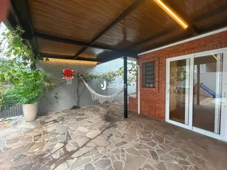 Pátio externo com piso de pedra e parede de tijolos em Lajeado.