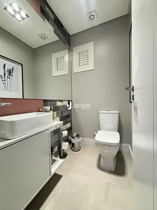 Interior de um banheiro moderno com bancada e vaso sanitário brancos.