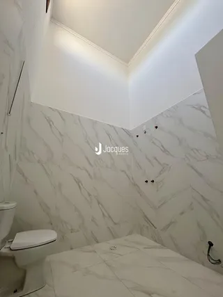 Banheiro com revestimento de mármore nas paredes e piso.