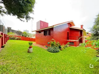 Fachada de casa em tijolo vermelho com gramado verde.