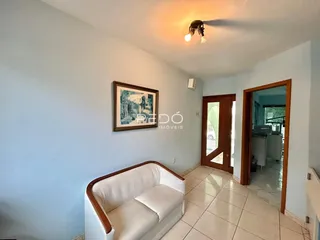 Sala de estar com sofá branco e piso de cerâmica clara.