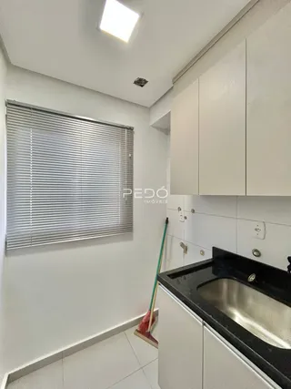 Interior de uma cozinha com armários brancos e janela.