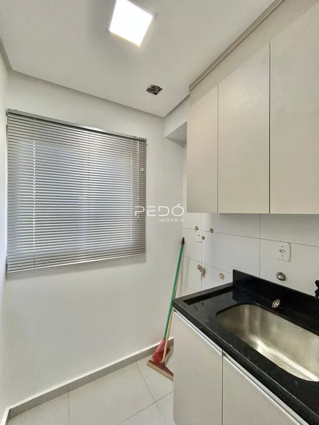 Interior de uma cozinha com armários brancos e janela.