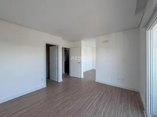 Vista interna de um ambiente com piso de madeira clara e paredes brancas.