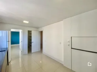 Hall de entrada com piso claro e armários brancos.