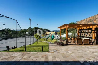 Vista externa de uma área de lazer com quadra esportiva e jardim.