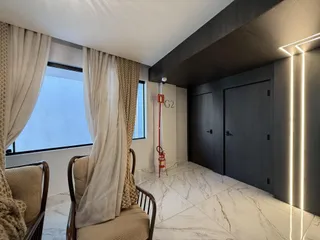 Sala de estar com grandes janelas e móveis de madeira em um apartamento.