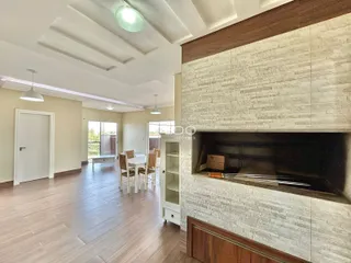 Sala de estar com piso de madeira e parede de lareira em um imóvel no Brasil.