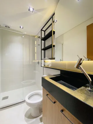 Foto de um banheiro moderno com box de vidro e louças brancas.