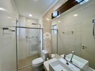 Imagem de um banheiro moderno com box de vidro e louças brancas.