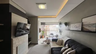Sala de estar com sofá e televisão montada na parede.