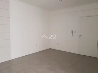 Ambiente interno de uma sala com paredes brancas e piso claro.