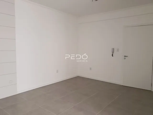 Ambiente interno de uma sala com paredes brancas e piso claro.