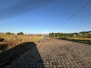Uma estrada pavimentada atravessa uma área de campo gramado sob um céu azul.